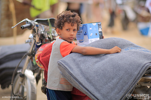 A child from Yemen standing next to a motorbike.