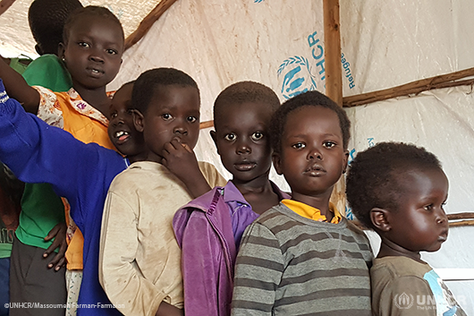 Refugee children from South Sudan wait in a shelter with their families.