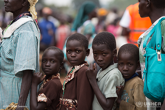 Refugee children from South Sudan wait with their mothers for core relief supplies.